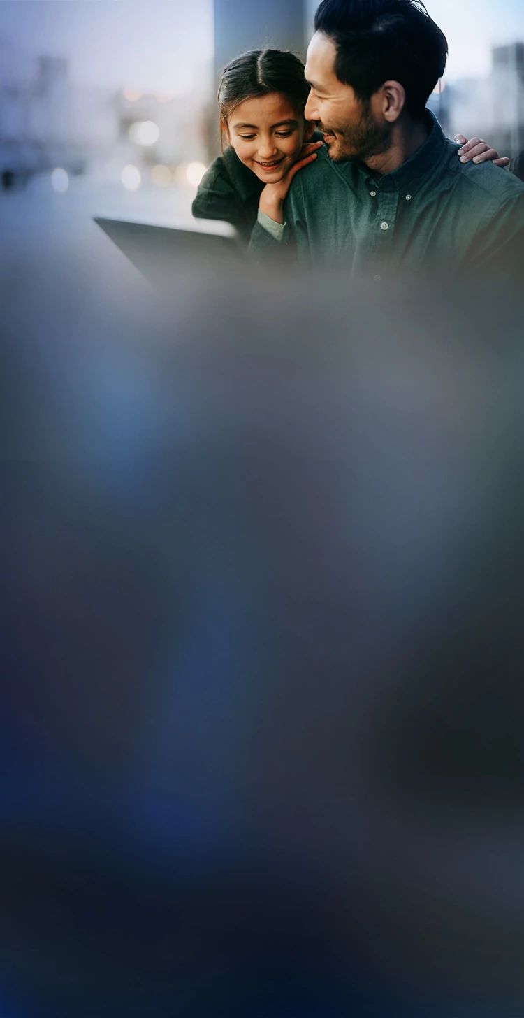 Parent and child smiling while using a tablet to stream content.